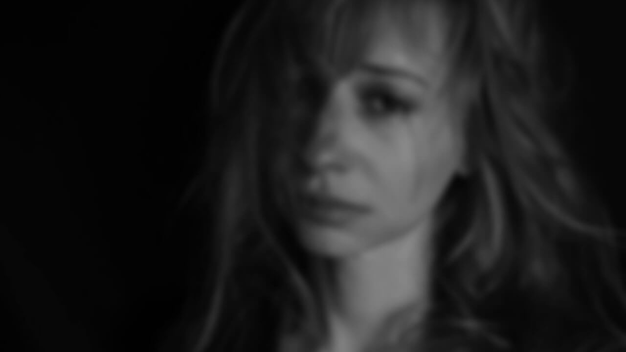 Female crying against a black background