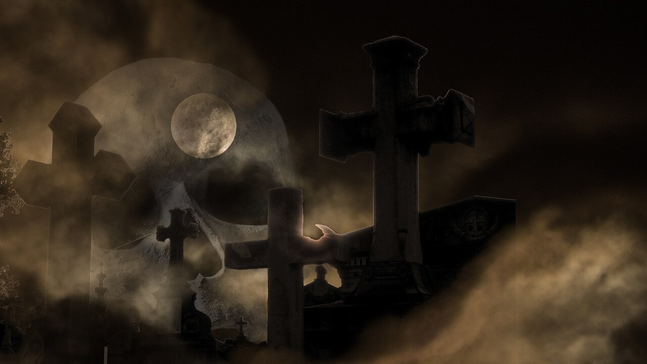 A dark photo of a graveyard with crosses buried