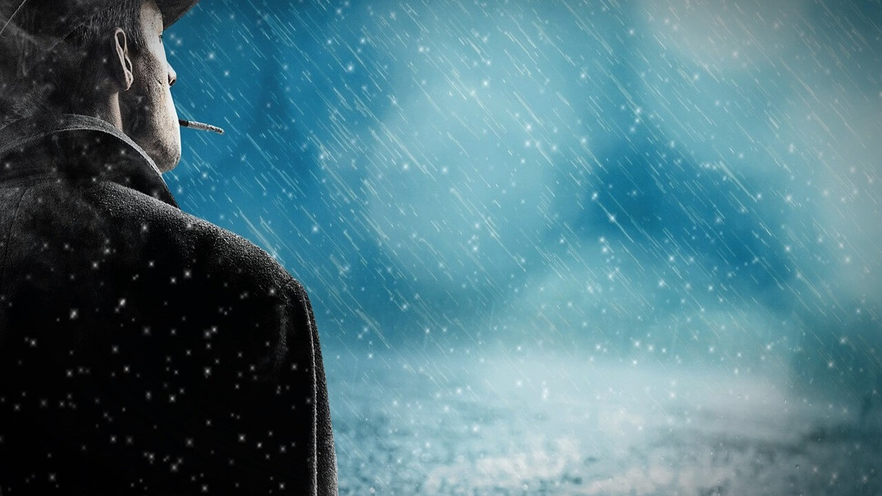 Unknown man dressed in black, standing in the rain or snow, smoking a cigarette