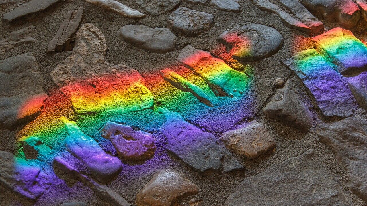 A rainbow reflection upon a bunch of gray rocks